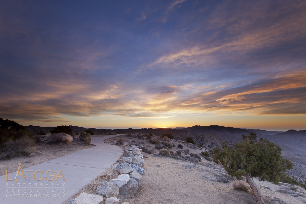 A sidewalk winds off toward the distant rising sun at Keys View, Joshua Tree National Park, California.